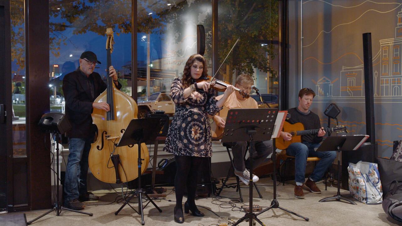 Alisha playing violin with her band